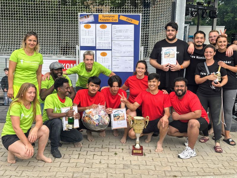 Team mit Wanderpokal und Urkunden vor Spielplan Keppler-Cup