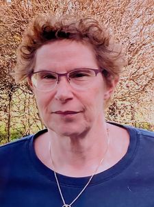Porträt einer Frau mit kurzen lockigen Haaren und Brille